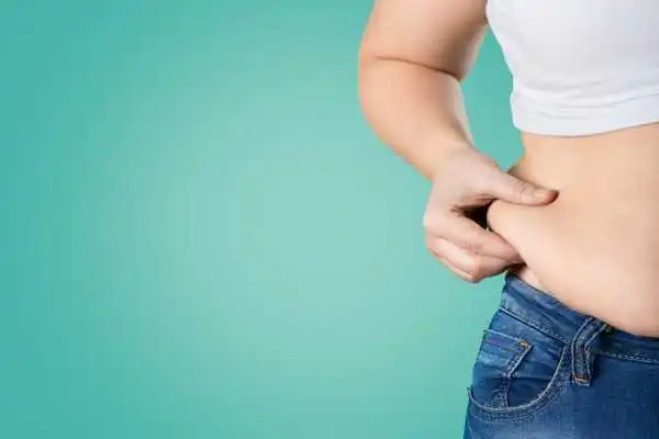 Image of woman pinching her love handles to show weight gain Harrow
